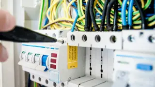En elektriker justerar en säkring i elcentralen, en viktig del för att hålla nere driftskostnader villa.